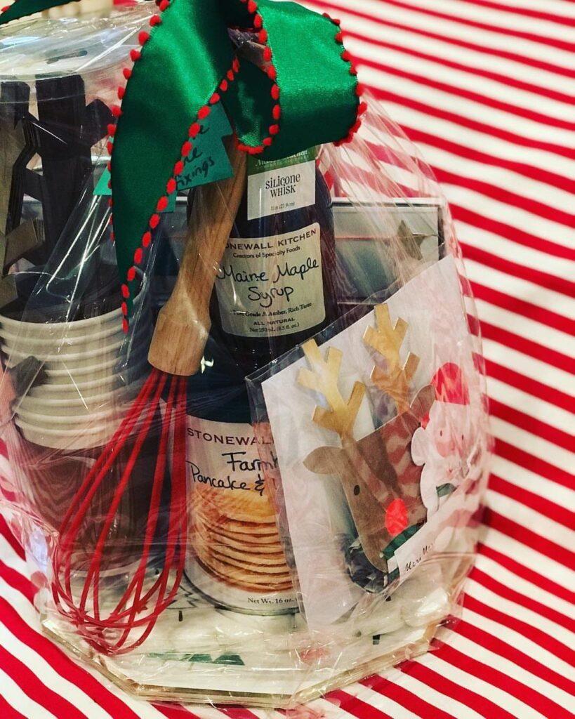 Pancake breakfast gift basket with syrup, mix, and utensils wrapped in clear cellophane.