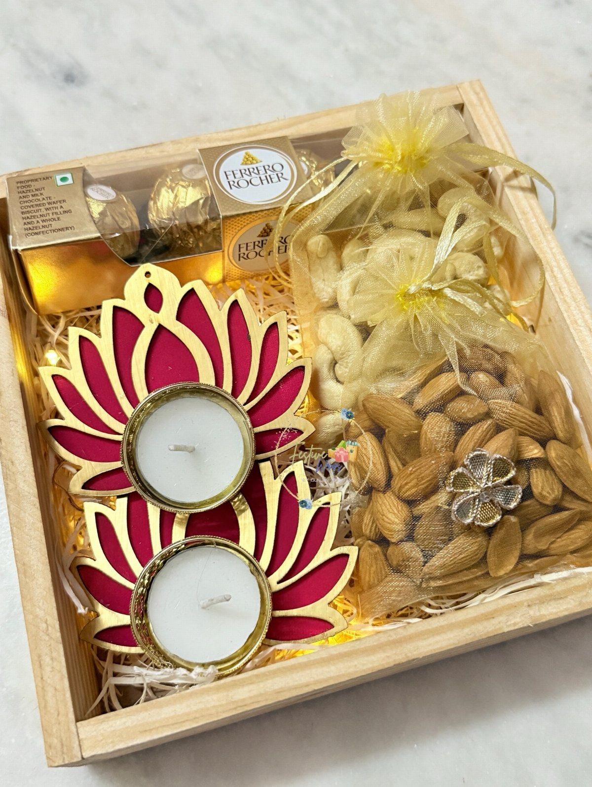 Wooden Diwali gift hamper with lotus tea lights, chocolates, and pouches of nuts.