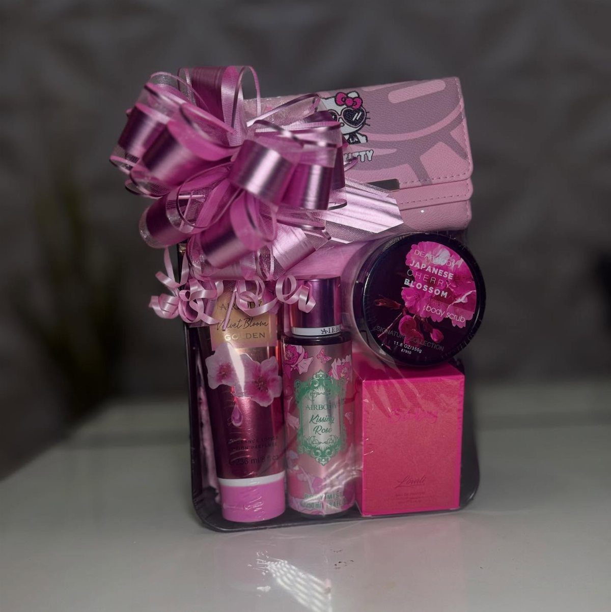 Pink spa gift basket with lotion, cream, and wallet topped with a satin bow