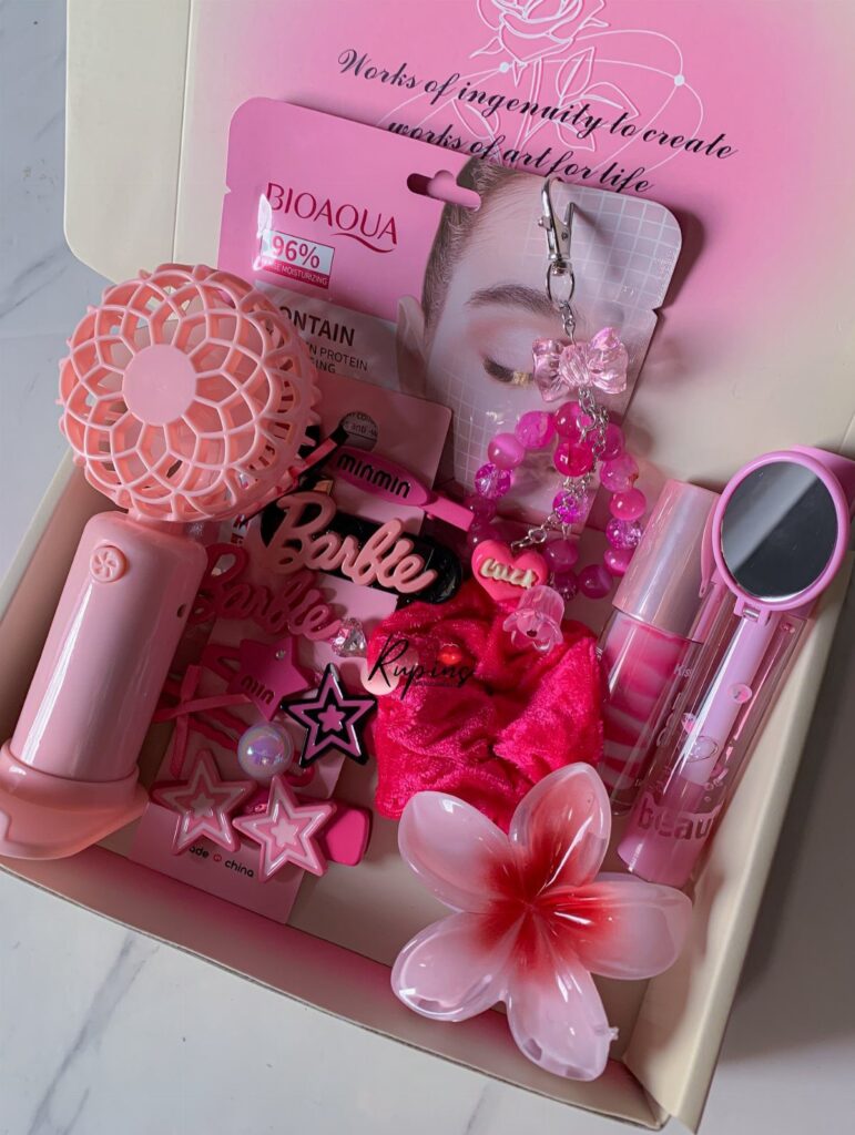 Pink beauty gift box containing a handheld fan, mirror, lip gloss, and accessories.