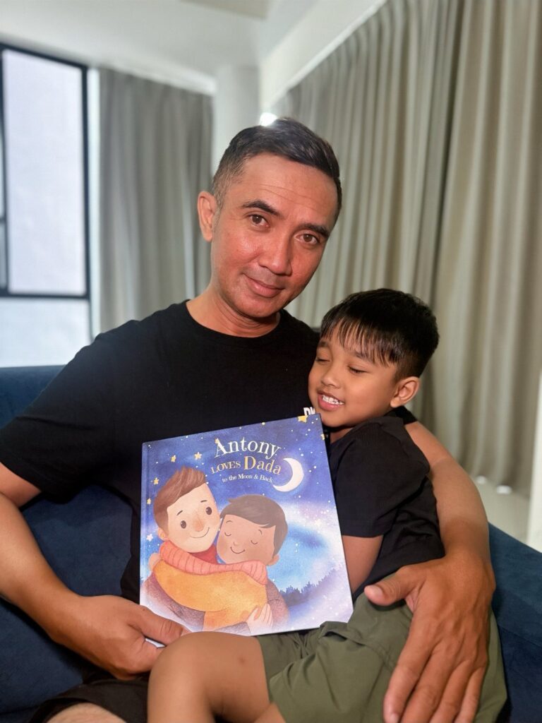 Father and son sitting on a sofa holding a personalized children's book.