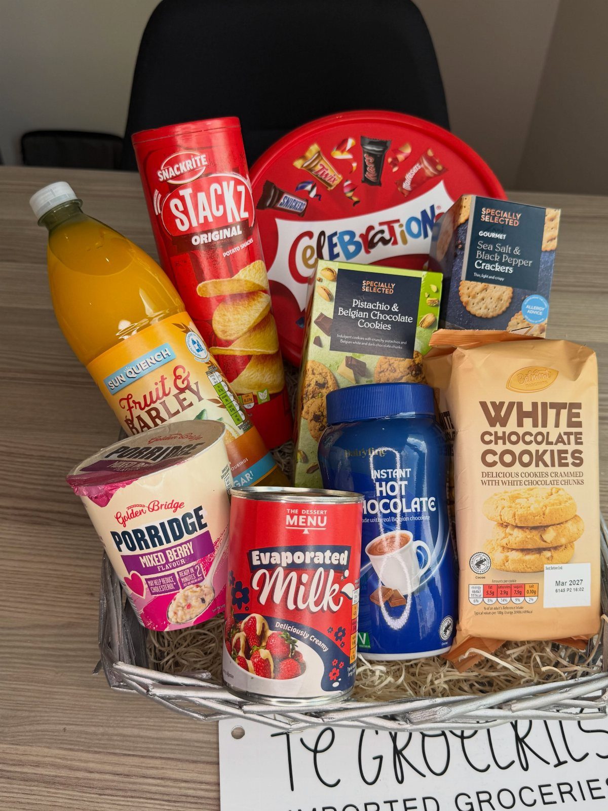 Grocery gift basket filled with snacks, juice, and pantry staples in a white basket.