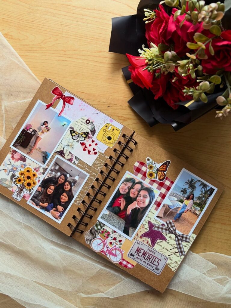 Handmade scrapbook with photos and stickers next to a bouquet of red roses.