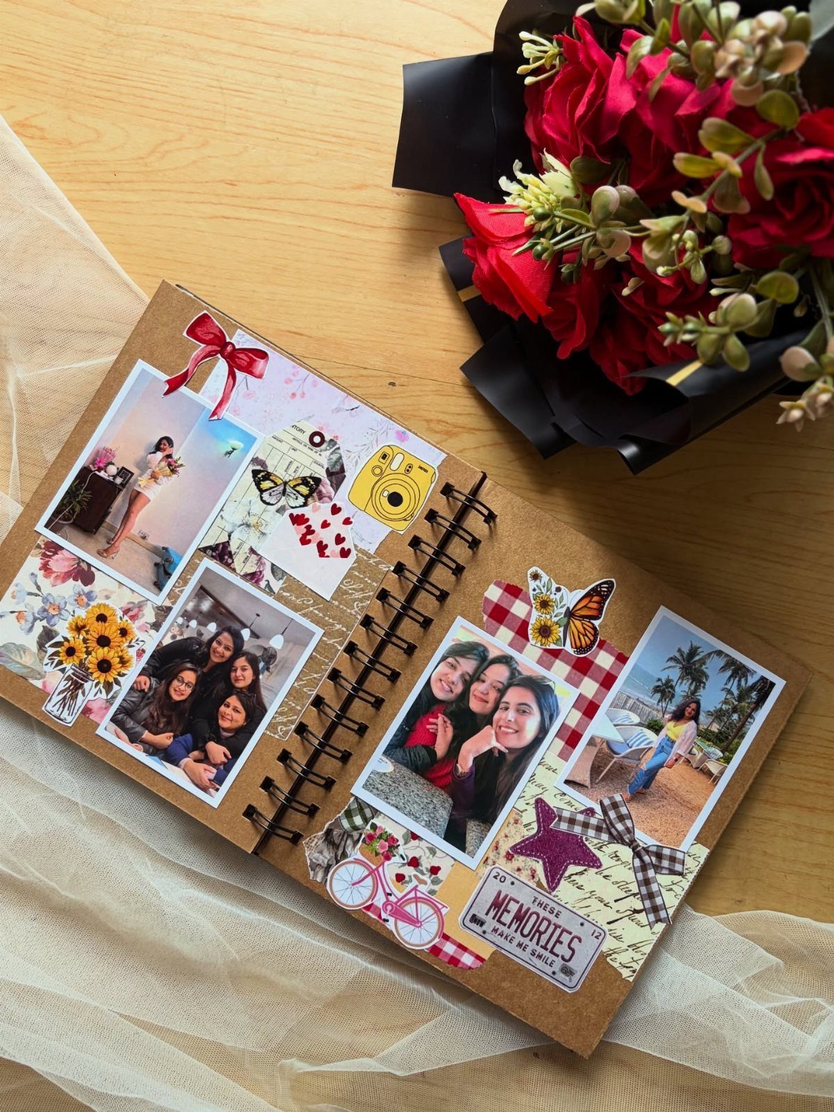 Handmade scrapbook with photos and stickers next to a bouquet of red roses.