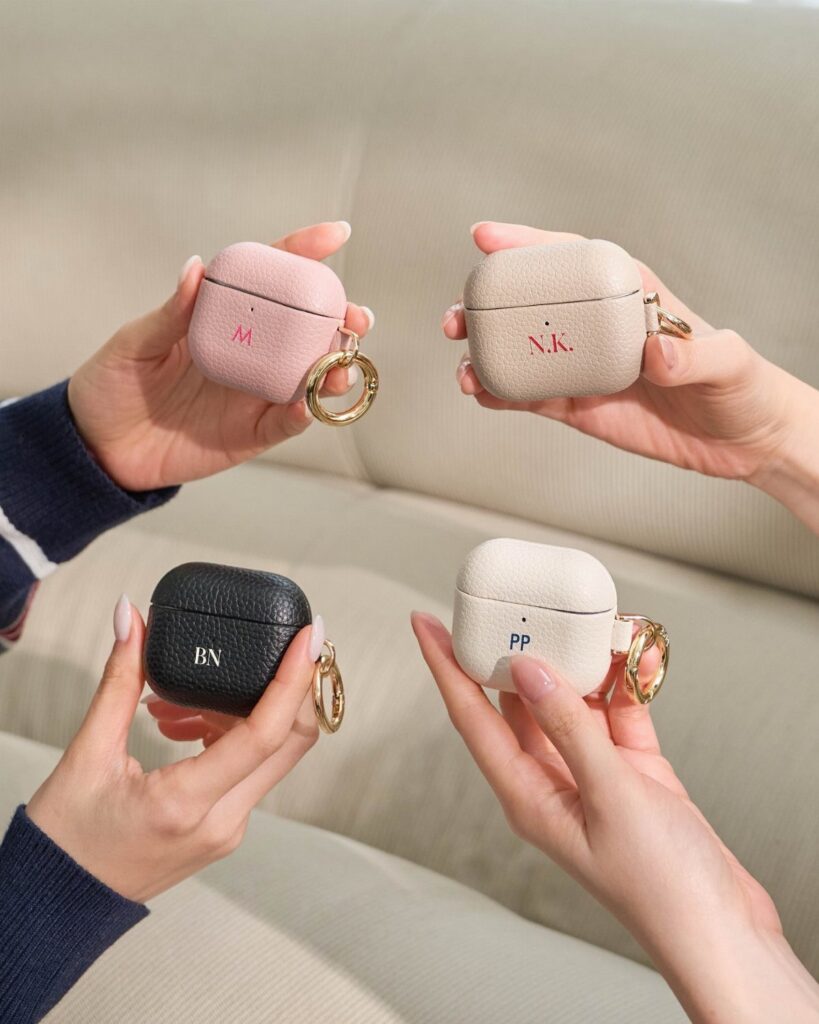 Four leather AirPods cases in different colors with personalized gold initials and rings.