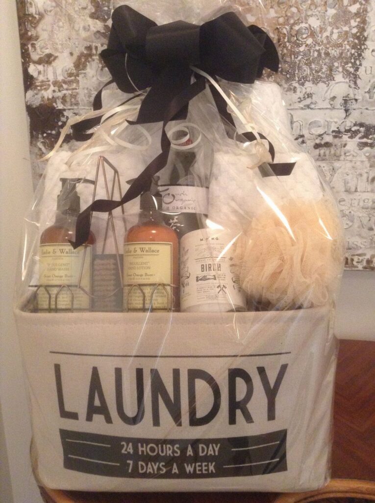 Laundry hamper gift basket wrapped in cellophane with a large black bow.