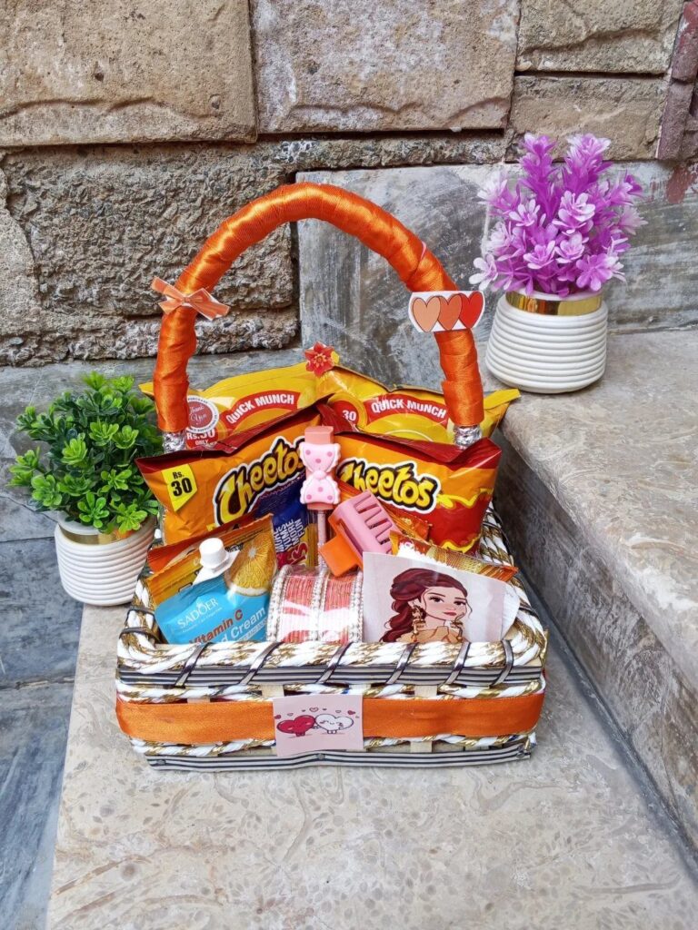 White woven gift basket filled with orange snacks and lotion on stone steps.