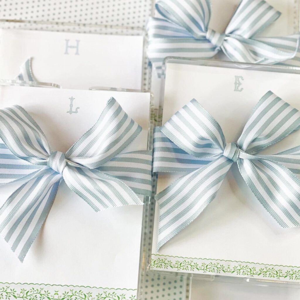 White cards with blue initials tied with striped blue and white ribbon bows.