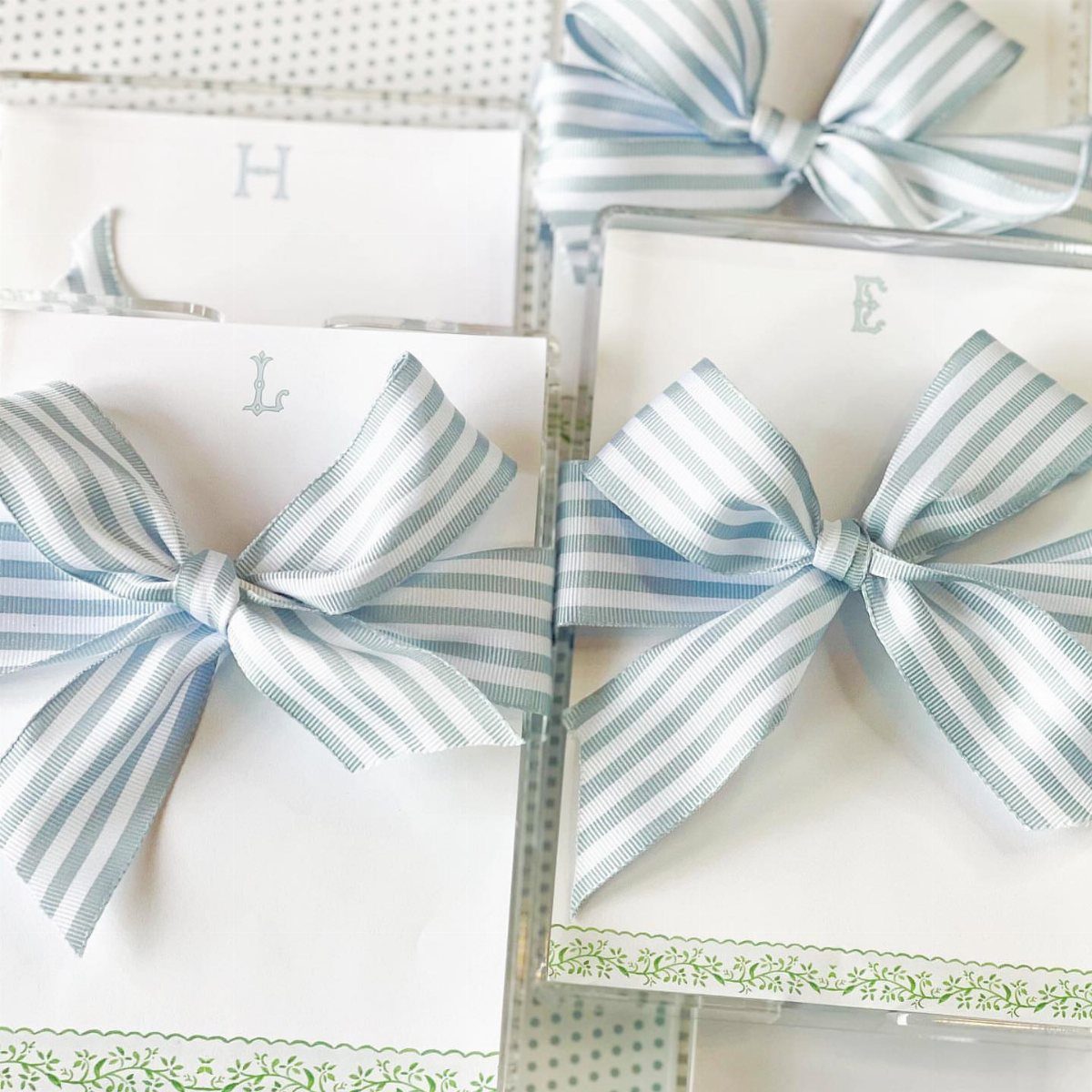 White cards with blue initials tied with striped blue and white ribbon bows.