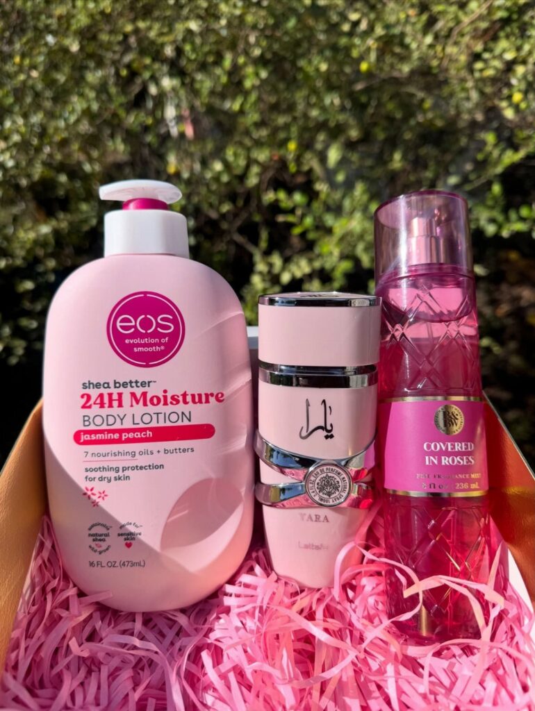 Pink body lotion, perfume, and fragrance spray in a pink shredded paper gift box.