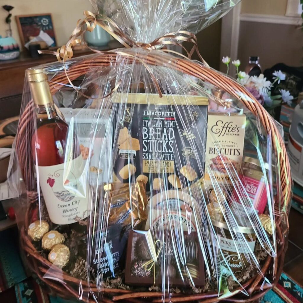 Wicker gift basket containing a bottle of rosé wine and various gourmet snacks.