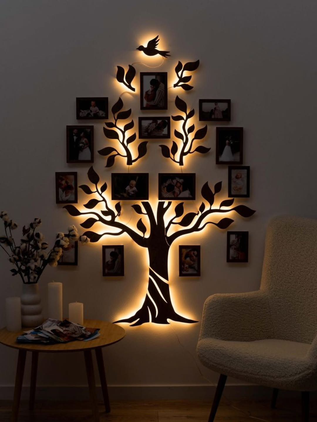 Backlit wooden family tree wall art holding small family photographs on a white wall.