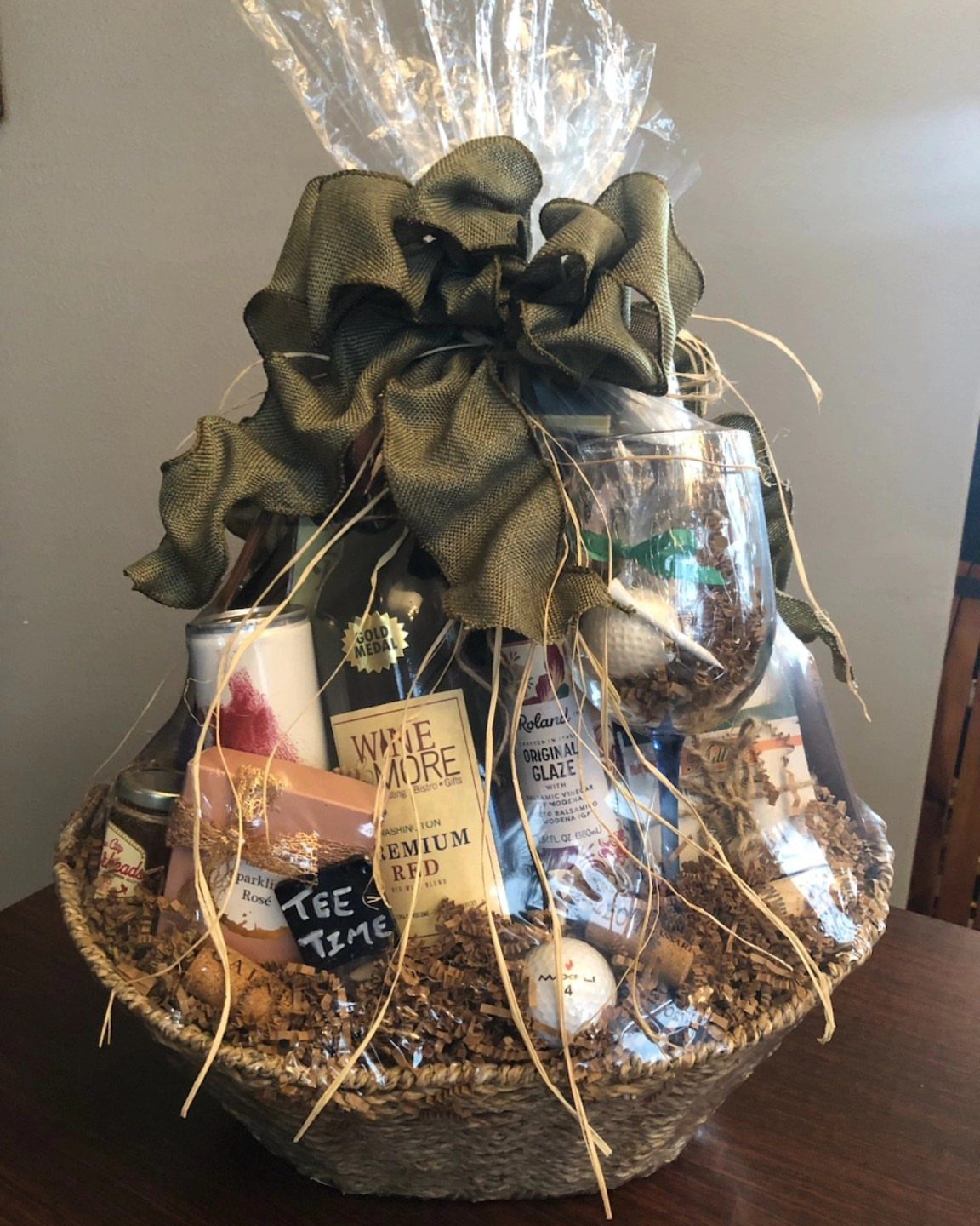 Wine gift basket with a bottle of red wine, glass, and green bow.