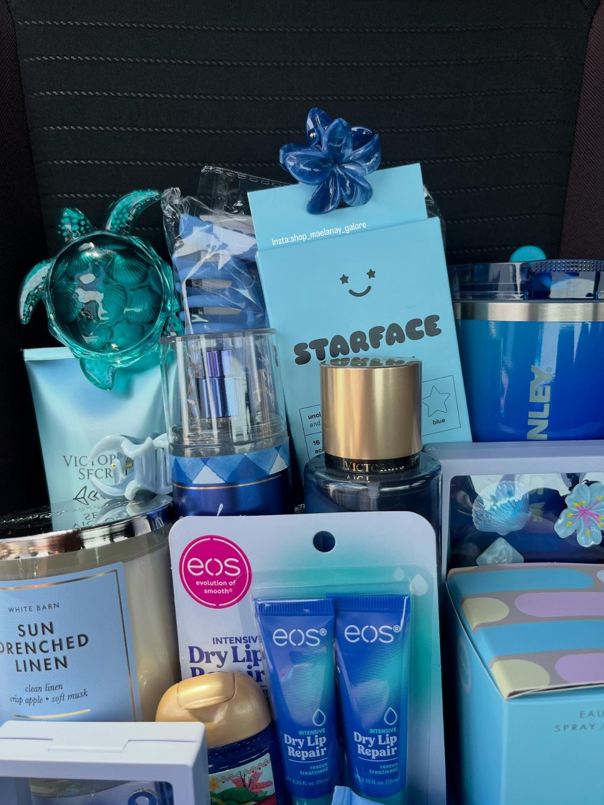 Blue themed gift basket with skincare products, a candle, and a turtle figurine.