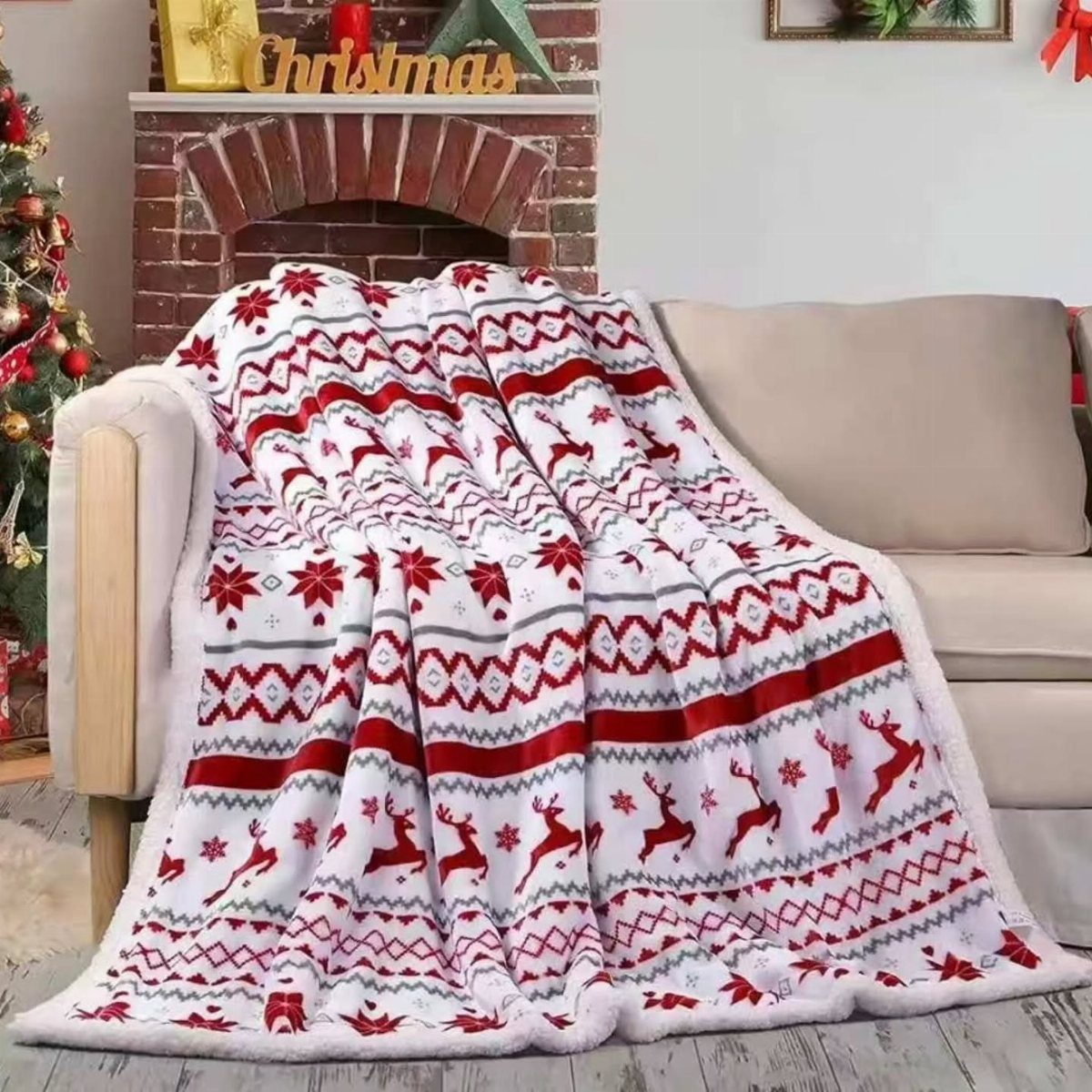 White fleece blanket with red reindeer patterns draped over a beige living room sofa.